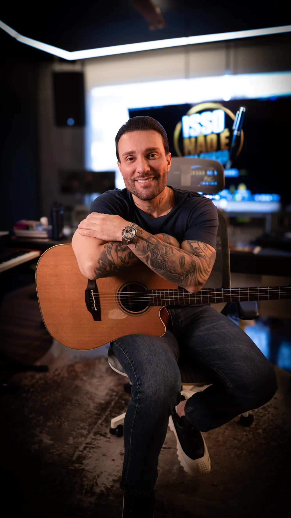 Bruno César sorrindo com o violão no estúdio